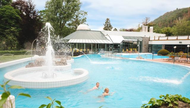 Aussenbecken mit großer Wasserfontaine und der Therme im Hintergrund